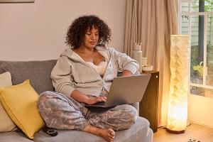 Person using laptop at home while wearing Medela Motion InBra wearable breast pump, highlighting hands-free, discreet pumping in everyday life