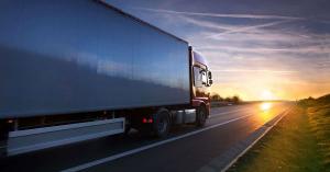 Commercial Truck driving down a long road at dusk