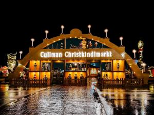 World's largest walk-on Christmas arch illuminated at night, displaying 'Cullman Christkindlmarkt' with traditional German wooden figurines and candle decorations in golden-lit display windows