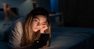 Teen or young adult using a phone late at night representing screen addiction, social media dependency, emotional withdrawal, and unhealthy routines.