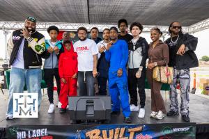 Group photo from the Built Different Youth Empowerment & Mental Wellness Summit in Compton featuring community leaders, mentors, artists, youth attendees, and organizers standing together on stage during the event.