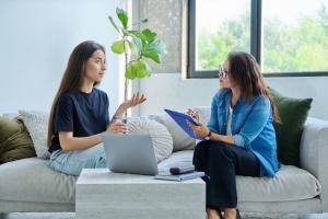 A Therapist in session seating on a sofa with a teenager