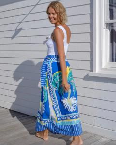 A model wearing a BAYE London one shoulder white swimsuit and a wrap front maxi skirt in a blue palm print