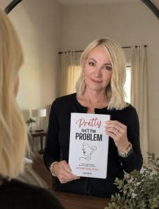 Author Shelli Netko reflection holding a copy of Pretty Isn’t the Problem: Why We Chase Beauty and Youth—and What Really Matters.
