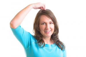 photo of a woman from waist up, tapping on the top of her head demonstrating tapping doing EFT