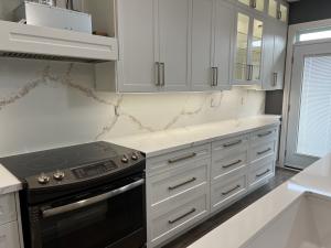 Custom quartz kitchen countertops and a full-height waterfall-veined backsplash installed by DreamStone Kitchen in the Greater Toronto Area.