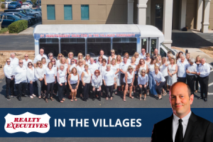 Realty Executives in The Villages in front of a branded, white bus with Broker/Owner Glenn Stein.