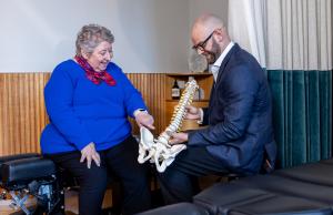 Dr David McNaughton shows patient Barbara Holmes a spine model demonstrating treatment.