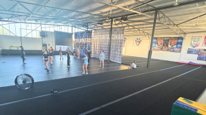 Interior view of the new 8,500-square-foot Cheer Athletics Telford facility featuring multiple training floors, athlete practice space, and championship banners celebrating the program’s growth and new home.