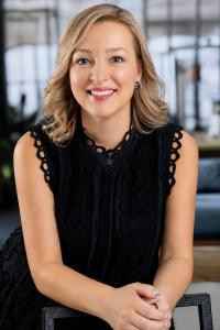 Tatiana Malinsky of IntraTEM poses in black blouse leaning on a table as she's appointed the company's new COO.