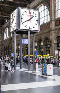 Official Swiss Railways Station Clock displayed inside a busy Swiss railway station.