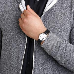 MONDAINE wristwatch with a white dial, black markers and red seconds hand worn on a person's wrist.