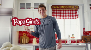Drake Maye smiling and standing in Papa Gino's kitchen holding a ball of pizza dough
