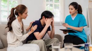 Photo of a counseling session with a health care counselor assisting a male client in apparent mental health crisis