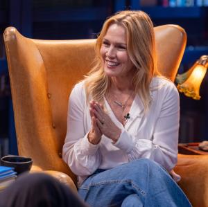 Jennie Garth laughs, sitting in a high-backed leather library chair on the set of Books That Changed My Life