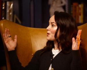 Jena Malone speaks excitedly, sitting in a high-backed leather library chair.