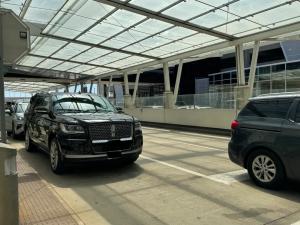 Black Lincoln Navigator SUV at airport pickup area