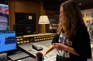 Kate Edge of Autonomy Music Group standing at a Solid State Logic mixing console in a professional recording studio