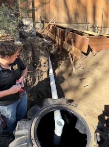 A technician overseeing a residential sewer repair and septic system connection.