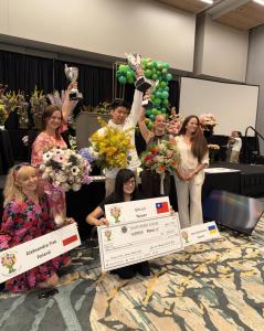 Winners of the 2026 Gateway to the Americas Cup International Floral Design Competition celebrate in Orlando, Florida. Overall champion Eric Lin of Taiwan stands with second-place winner Aleksandra Flak of Poland and third-place winner Anna Dementieva of