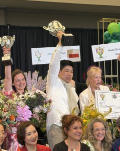 Eric Lin of Taiwan raises the championship trophy after winning the 2026 Gateway to the Americas Cup International Floral Design Competition in Orlando, Florida.