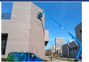 Crane-assisted installation of custom police badge signage in downtown Louisville
