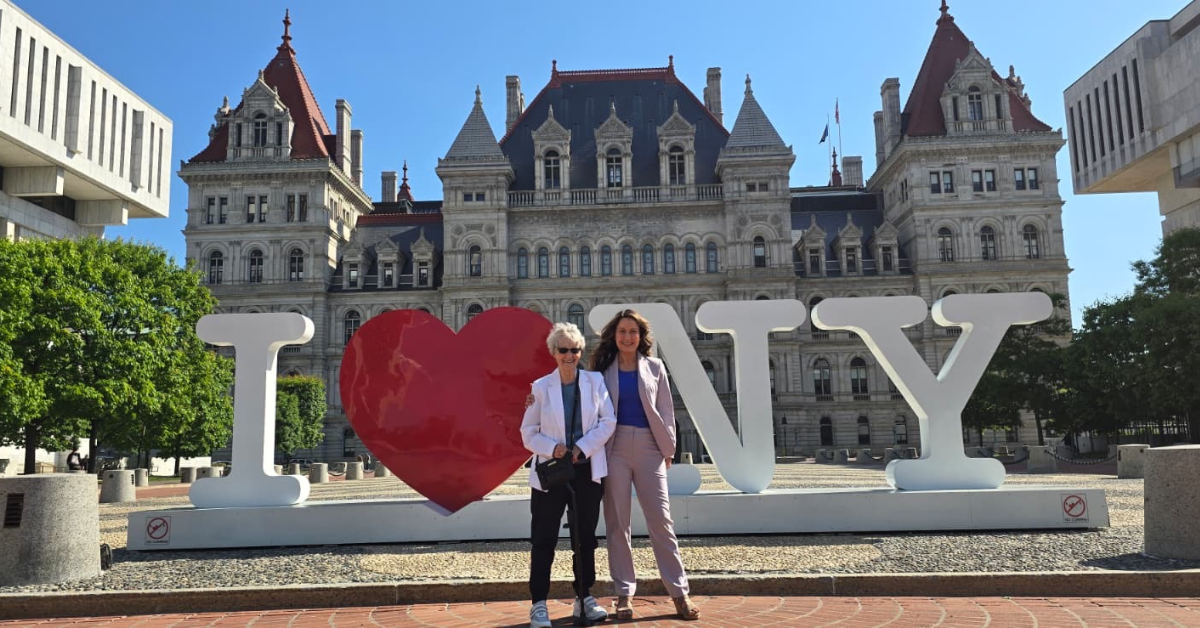 Susan Herson MD and her Mom, Sallie Herson stand on a sunny day in front of giant letters I ❤️ NY