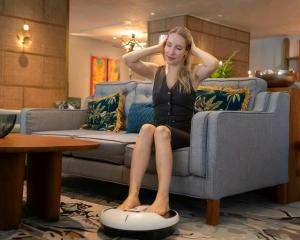 TerraTech Seated Treadmill home wellness device being used by a woman relaxing on a living room sofa