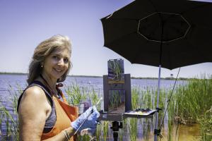 Artist Susan Knowlton paints at the edge of Lake Shelby on a sunny day