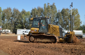 A Caterpillar bulldozer performing precision earthwork on a construction site using advanced GPS grading equipment.