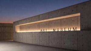 Dezente Lichtwerbung an einer modernen Museumsfassade mit beleuchteter Betonwand, klarer Beschriftung und hochwertiger Architekturbeleuchtung.