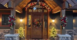Professionally decorated holiday entryway with custom wreath, garland, and lit Christmas trees at a mountain home in Durango, Colorado.
