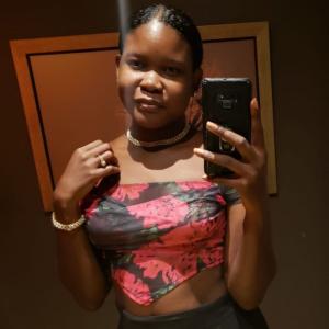 Beautiful black woman posing in mirror wearing blinged out necklace and bracelet from Amare Sui