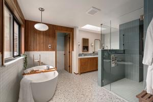 Mid-century modern bathroom remodel in Sammamish featuring vertical wood slat walls, terrazzo flooring, a freestanding soaking tub, blue tiled walk-in shower, and custom wood vanity.