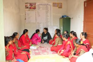 Image shows Prajakta Koli seated on the ground surrounded by members of a women-led cooperative in Nepal.