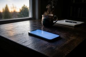 A phone in soft early morning light, warm and quiet, the glow of the screen.