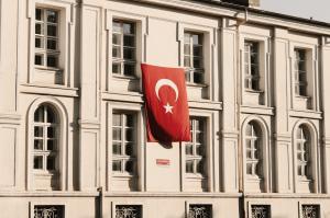A bright red Turkish flag waving against a sunny blue sky, featured in the 2026 Turkey Citizenship by Investment (CBI) report on global mobility.