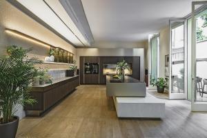 Modern SieMatic kitchen display at Milan Design Week 2026 featuring integrated lighting, dark wood cabinetry, a sculptural island, and floor-to-ceiling windows.