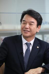 National Assembly Member Moon Jin-seok, wearing a dark suit and navy patterned tie with the National Assembly member pin on his lapel, photographed at the National Assembly, Seoul.
