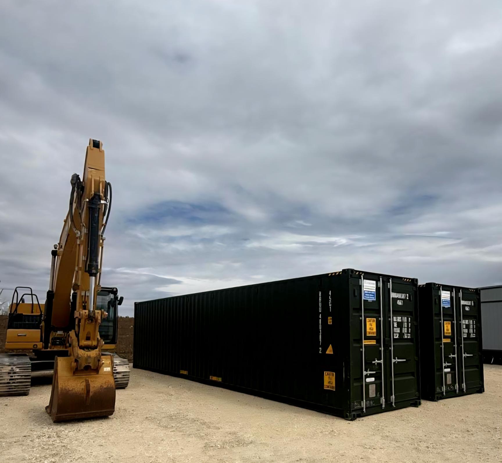 IMAGE CONTAINING TWO SHIPPING CONTAINERS NEXT TO A NEW EXCAVATOR AND A BRIGHT BLUE SKY WITH SOME CLOUDS