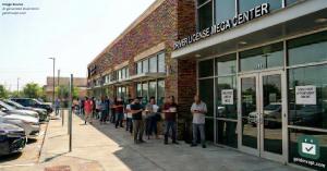 A long line of people waiting outside a Texas DPS mega center for a driver's license appointment on a bright sunny day, illustrating the months-long wait for a DPS appointment.