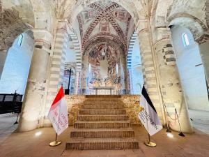 Interior view of the Abbazia di Santa Giustina in Sezzadio, Italy, featuring medieval architecture and frescoes.