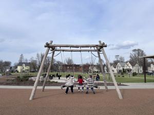 Children play on an outdoor play set under a crystal blue sky in Cleveland.