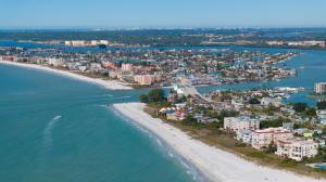 Aerial view of Pinellas County beach condos, white sand shoreline, blue water, and waterfront neighborhoods.