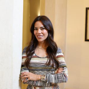 Zeynep Koseoglu, Founder of The Plum Edit. Stood with her arms folded in a patterned dress.