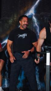 A person wearing a Junk Yard Fitness T‑shirt exercising indoors with colorful lighting effects in the background.