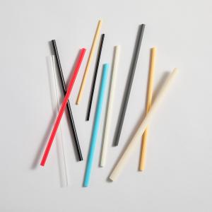 A variety of colorful compostable straws arranged on a dark surface, representing sustainable alternatives to plastic.