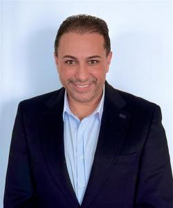 Man with suit jacket smiling at camera with light background