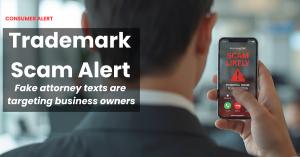 Businessman viewing a "Scam Likely" fraud warning on his smartphone, representing fake trademark attorney scam alerts.