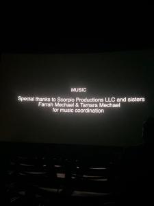 Film credits displayed on a theater screen recognizing Scorpio Productions LLC, Farrah Mechael, and Tamara Mechael for music coordination.